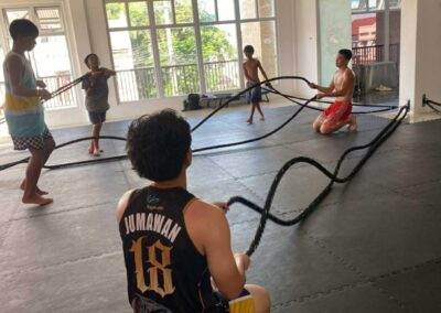 Young students at Philippine Top Team performing high-intensity waves with combat ropes during a youth athletic training session.