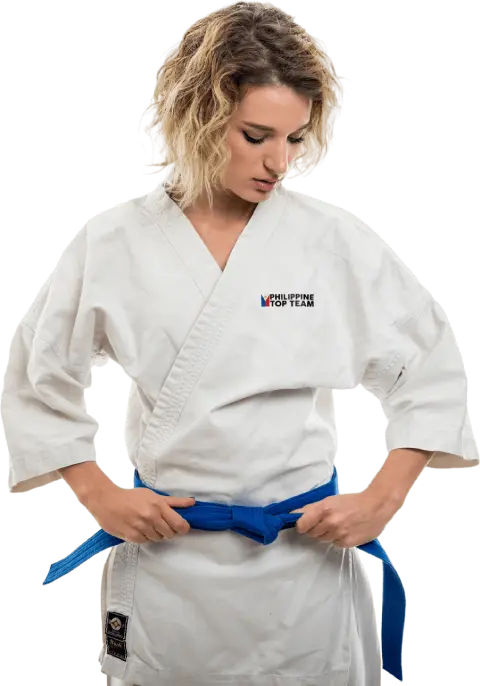 A female student at Philippine Top Team wearing a white Jiu-Jitsu gi and blue belt, posing in a martial arts stance.